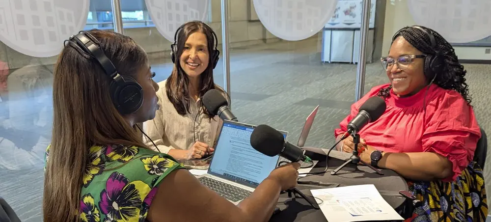 Lead IDEA Center experts Dia Jackson, Ph.D., and Dena Slanda, Ph.D. join Lead IDEA Center Leader in the Field Equetta Jones around a table. They are wearing headphones and a microphone sits in the middle of the table as they prepare to record a podcast.